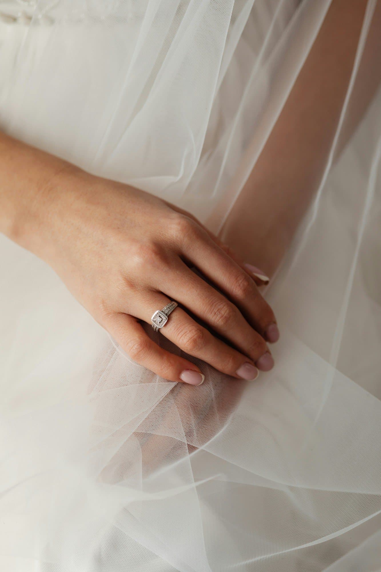 La main d'une mariée posée sur le tulle de sa robe, une bague au doigt
